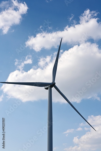 Onshore windmill power plant. The scattered white clouds contrasted with the blue sky and windmills.  The concept of using circulating wind to generate electricity.   © Vanchuree