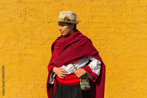 Hispanic peasant woman in traditional dress posing in front of a rustic yellow wall