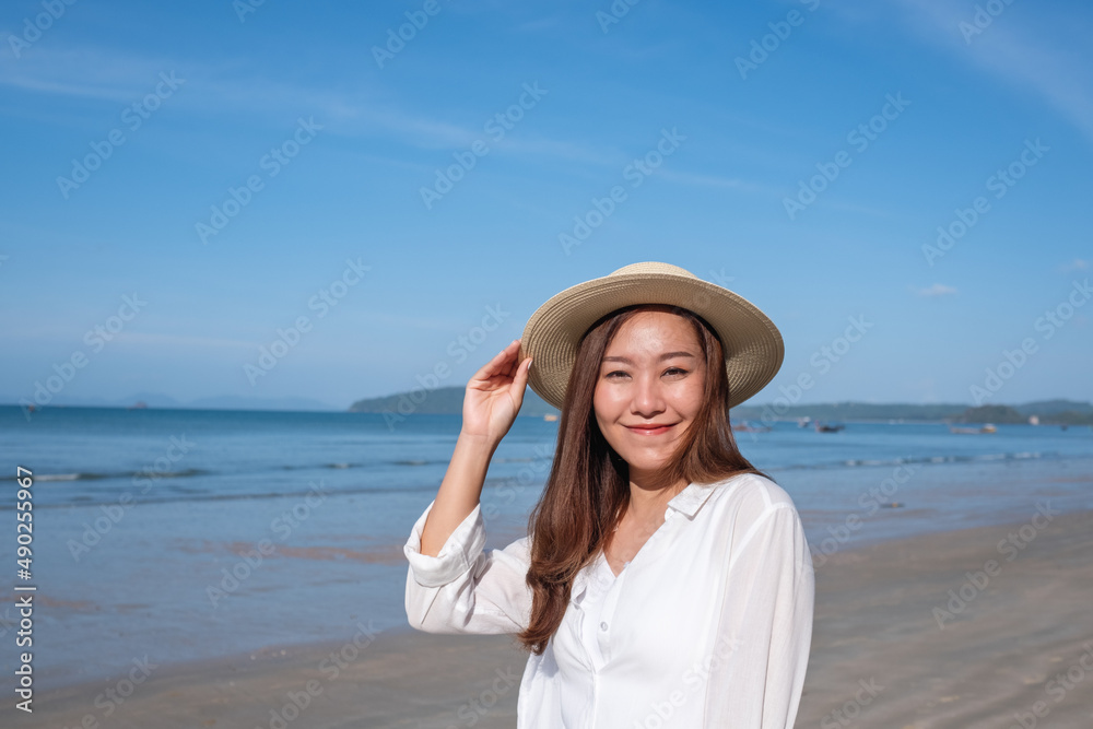 Portrait image of a beautiful young asian woman strolling on the beach with the sea and blue sky background Portrait image of a beautiful young asian woman strolling on the beach with the sea and blue sky background