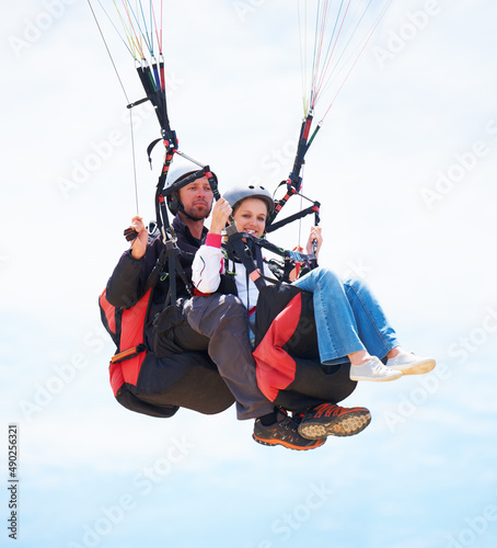 This is what birds must feel like. Portrait of two people doing tandem paragliding in mid-air.