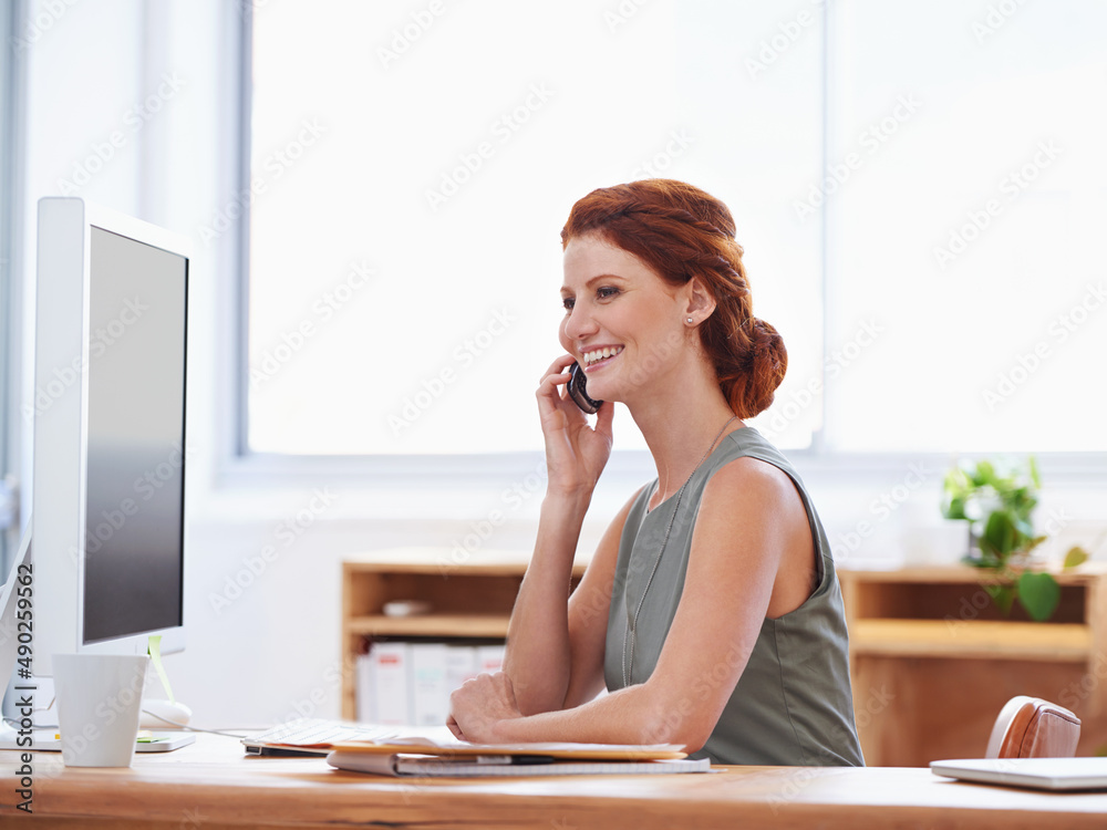 Following up with a client. Shot of an attractive young businesswoman talking on the phone while sitting at her desk.