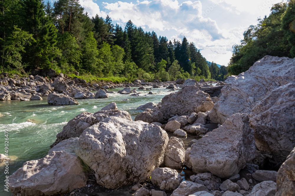 River Gail flowing through the Schuett in the natural park Dobratsch in Villach, Carinthia, Austria. Gailtaler and Villacher Alps. Riverbank is full of massive rocks. Swimming in crystal clear water River Gail flowing through the Schuett in the natural park Dobratsch in Villach, Carinthia, Austria. Gailtaler and Villacher Alps. Riverbank is full of massive rocks. Swimming in crystal clear water