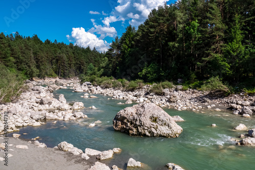 The river Gail flowing through the Schuett in the natural park Dobratsch in Villach, Carinthia, Austria. Gailtaler and Villacher Alps. The riverbank is used as a beach. Swimming in crystal clear water