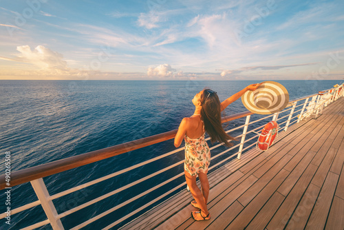 Cruise ship fun happy travel tourist woman enjoying sunset on deck feeling free with open arm relaxing at scenic view of ocean.
