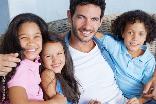 We share the strongest of family bonds. Portrait of a happy single parent family sitting on a sofa and smiling at the camera.