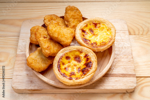 Fried chicken nuggets with egg tart on wooden background.
