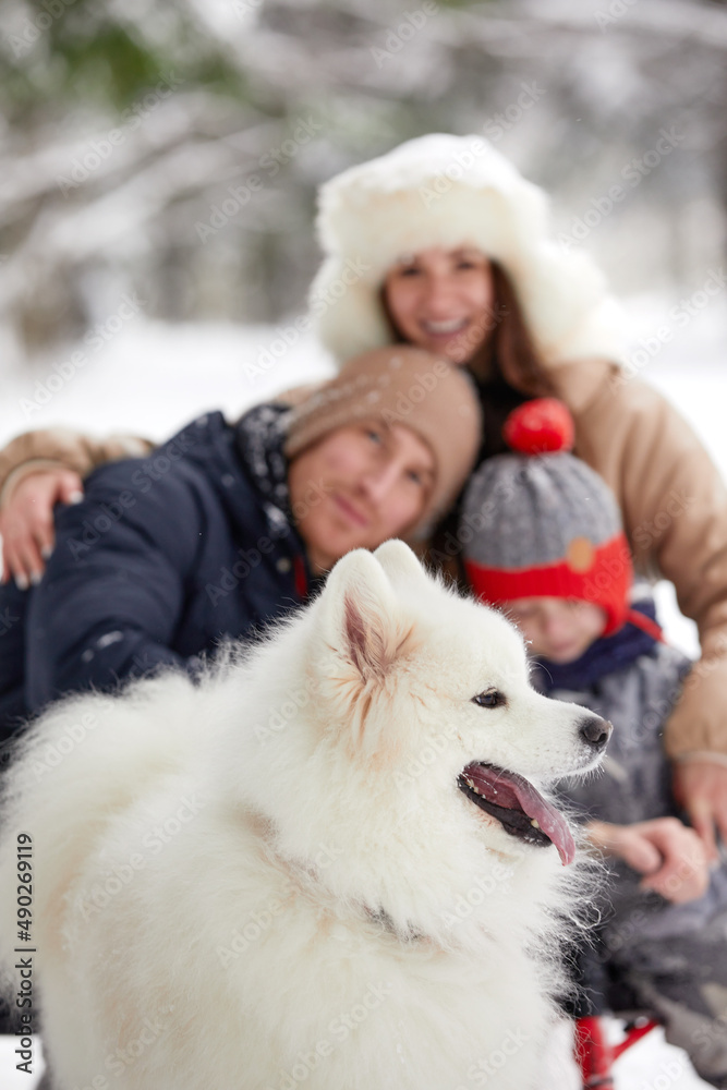 Family of mother, father and son having fun in snowy winter wood with cheerfull pet dog. Family of mother, father and son having fun in snowy winter wood with cheerfull pet dog.