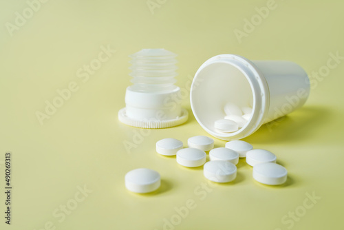 White painkiller pills in jar on yellow backdrop. Health care and medicine concept