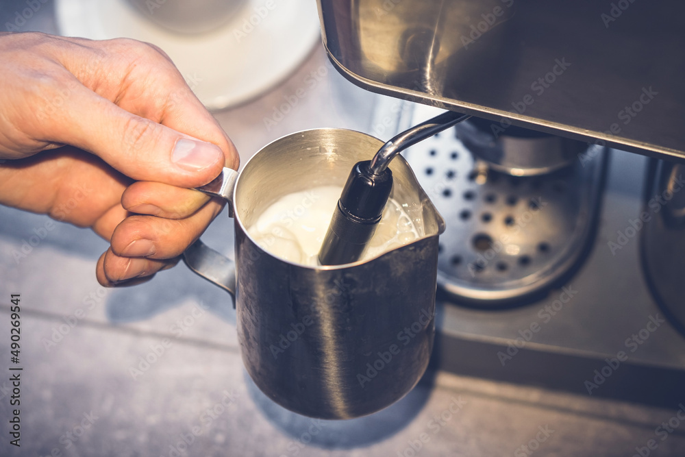 Cappuccino preparation. Barista beating milk in milk seller. Steamer. Coffee machine. Closeup Cappuccino preparation. Barista beating milk in milk seller. Steamer. Coffee machine. Closeup
