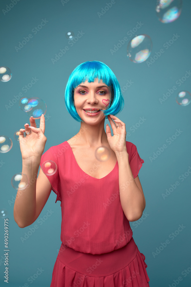 Beautiful young woman with blue wig and bright make-up in soap bubbles. Fashion model girl with creative color makeup. Women doll concept. Beautiful young woman with blue wig and bright make-up in soap bubbles. Fashion model girl with creative color makeup. Women doll concept.