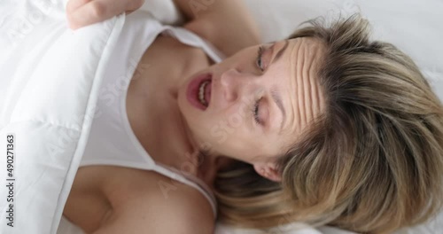 Waking woman lifts the blanket and looks in shock under covers photo