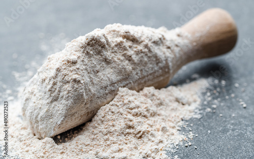 Spelt flour in wooden spoon on dark background