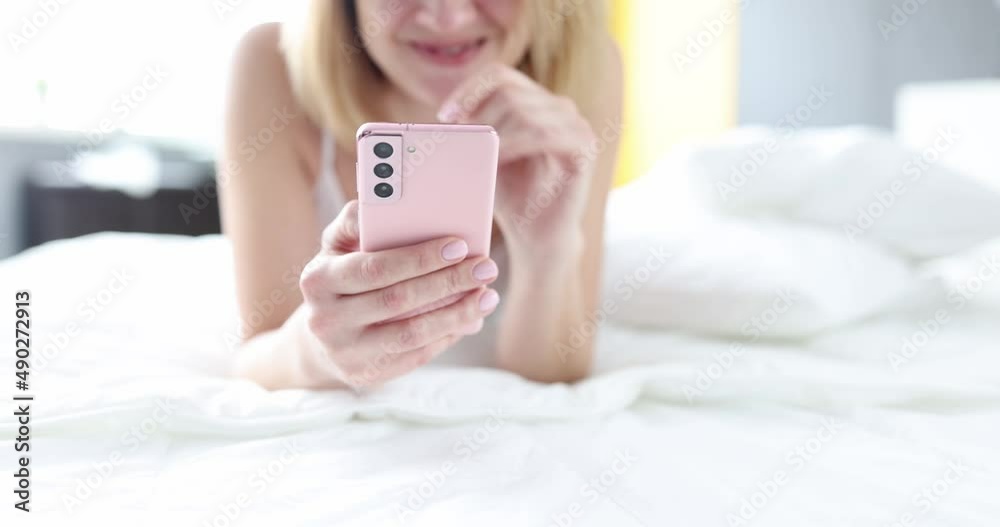 Smiling woman looking into smarphone while lying on phone Smiling woman looking into smarphone while lying on phone