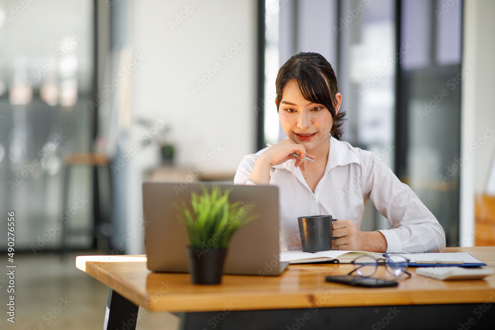Shot of an Asian young businesswoman working on laptop in her workstation. Shot of an Asian young businesswoman working on laptop in her workstation.