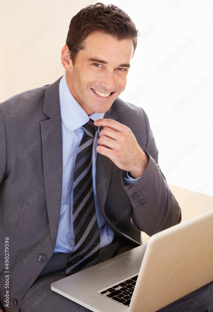 Hes a savvy businessman. Portrait of a handsome young businessman using his laptop. Hes a savvy businessman. Portrait of a handsome young businessman using his laptop.