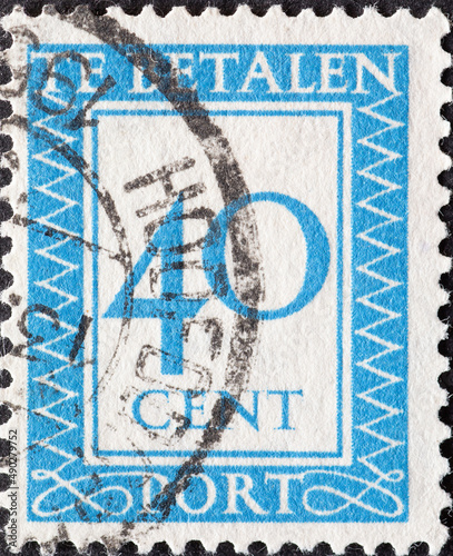 Netherlands - circa 1947: a postage stamp from the Netherlands , showing a number with an ornamental border. In blue.Text: The postage has been paid. Postage due . 40 cent photo