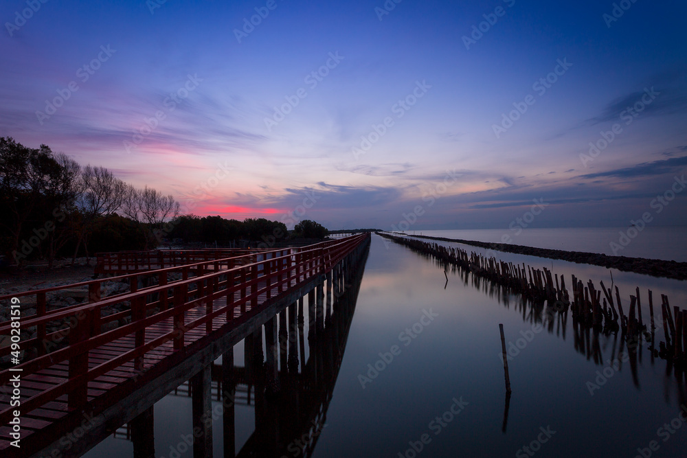 Sunrise and beautiful sky background at wooden red bridge over the sea at Gulf of Thailand, near by Tha Chin estuary, Samutsakhon province, Thailand 