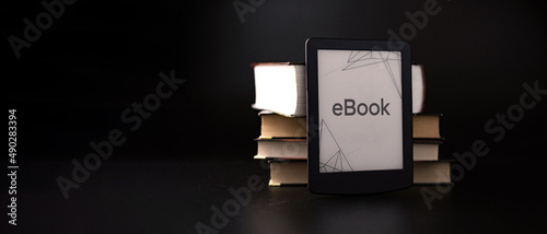E reader. Digital e book, library reader tablet with books on dark background. Online education course, E learning class and ebook digital technology concept. photo