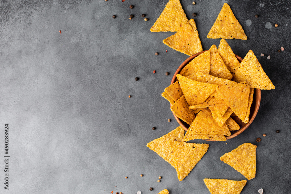 Corn Mexican tortilla chips snack on a black dark background. Food photo decorated with ketchup tomato sauce and salt. Corn Mexican tortilla chips snack on a black dark background. Food photo decorated with ketchup tomato sauce and salt.