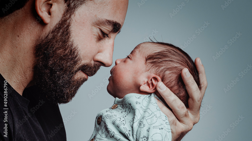 portrait of man looking at his newborn son with loving expression - obrazy, fototapety, plakaty 