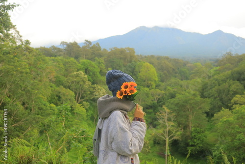 A girl holding flowers and standing in the green landscape 1 © Wia