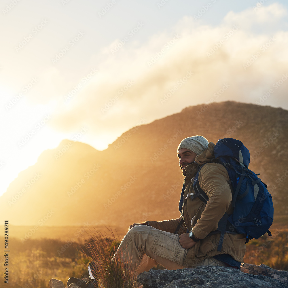 Embrace yourself and you embrace the world. Shot of a hiker sitting on top of a mountain smiling.