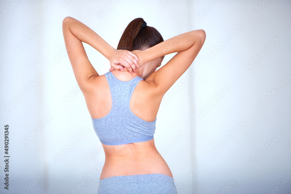 Obraz premium Stretching it out. Rearview of a young woman holding her neck and stretching.