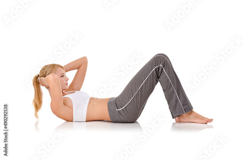 Ab-alicious. Full-length studio shot of a young woman doing sit-ups on the floor.