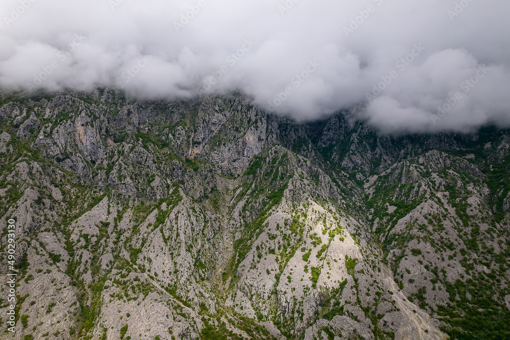 Aerial view of beautiful rocky mountains covered with clouds in Kotor bay, Montenegro