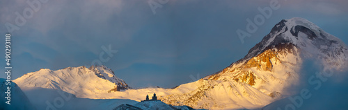 Sunrise panoramic view of Kazbek mountain peak and famous Gergety Trinity church in Kazbegi, Georgia