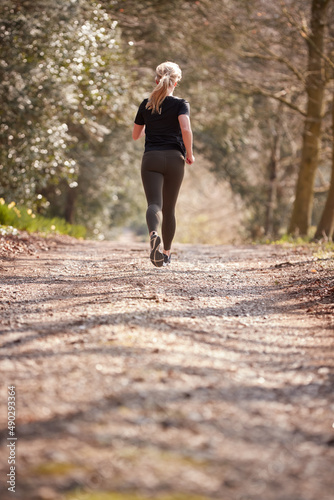 Rear View Of Young Woman Running In Autumn Countryside To Improve Mental Health During Lockdown