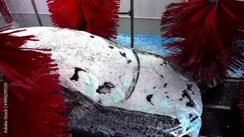 Black car moving though automatic car wash machine. The brush moving to clean the car. Slow motion shot
