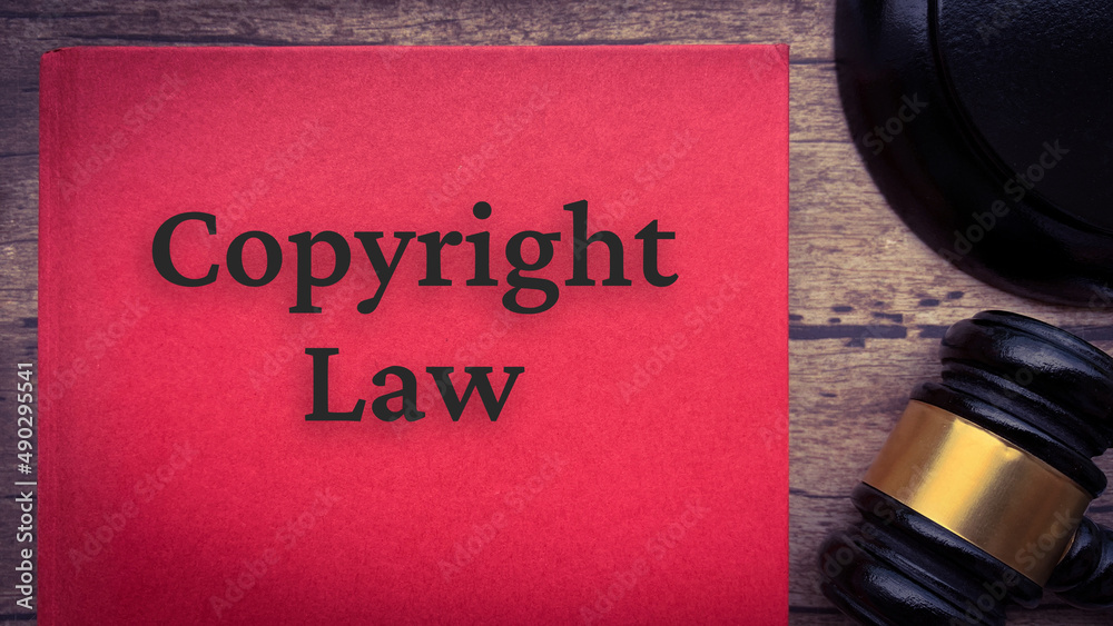Copyright law book and gavel on a brown wooden table. Copyright law book and gavel on a brown wooden table.
