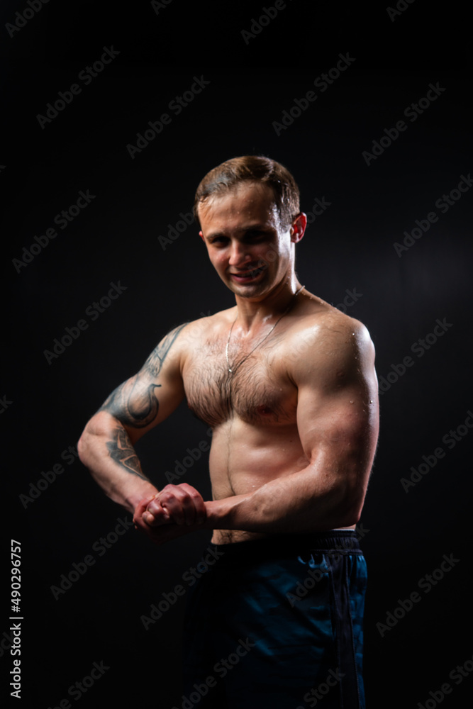Man on black background keeps dumbbells pumped up in fitness bodybuilding biceps black, body training workout athletic healthy pectoral. Young sportive power, guy fit View from the bottom up good Man on black background keeps dumbbells pumped up in fitness bodybuilding biceps black, body training workout athletic healthy pectoral. Young sportive power, guy fit View from the bottom up good