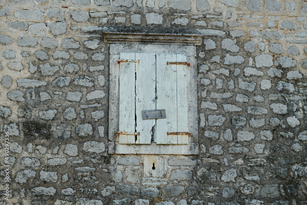 the stone wall is old and the window is shuttered the stone wall is old and the window is shuttered