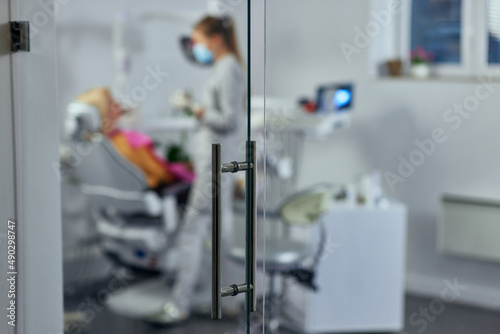 Mouth checkup at the young dentist's office behind glass door