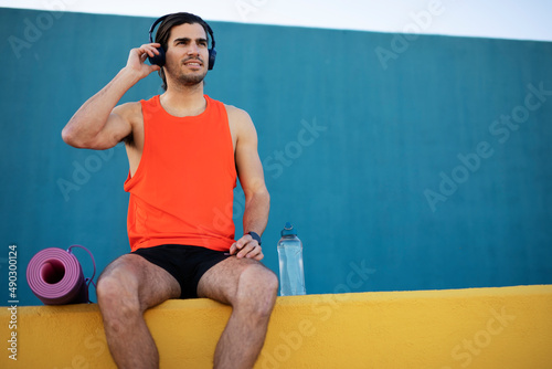 Young sexy man training outside. Fit handsome man listening the music.