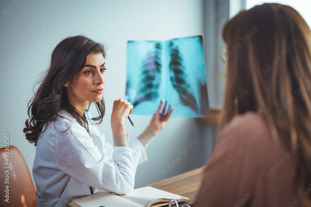Female doctor showing x-rays to patient. Healthcare worker is discussing with woman. They are in hospital. Female Doctor explain x-ray chest result to illness female patient Female doctor showing x-rays to patient. Healthcare worker is discussing with woman. They are in hospital. Female Doctor explain x-ray chest result to illness female patient