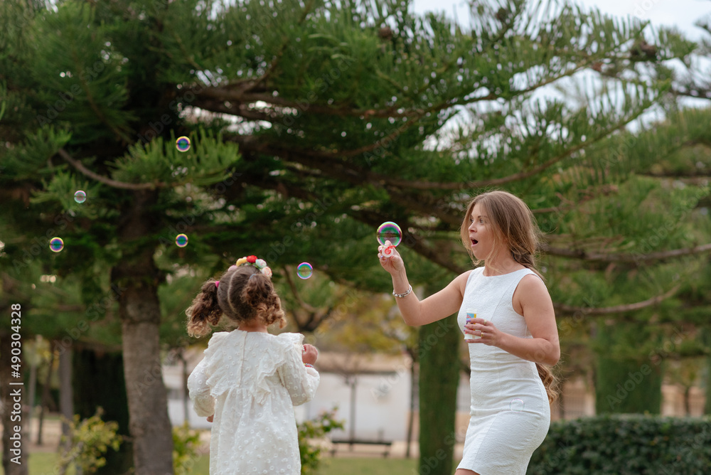 Fototapeta premium Mother and daughter blow soap bubbles outdoors.