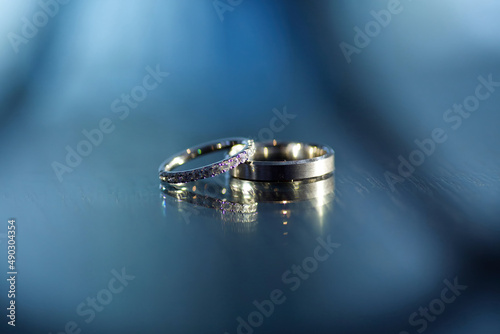 Wedding rings for weddings lie on a mirror reflecting surface.