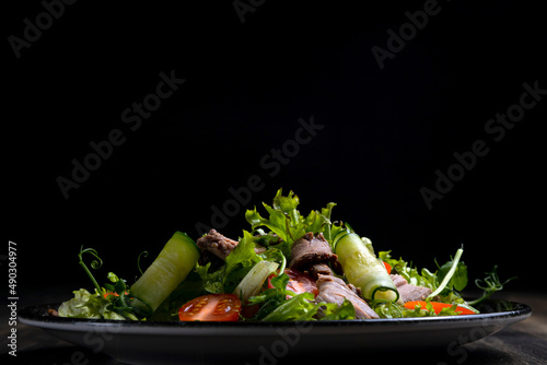 fresh vegetable salad and meat on dark wooden background