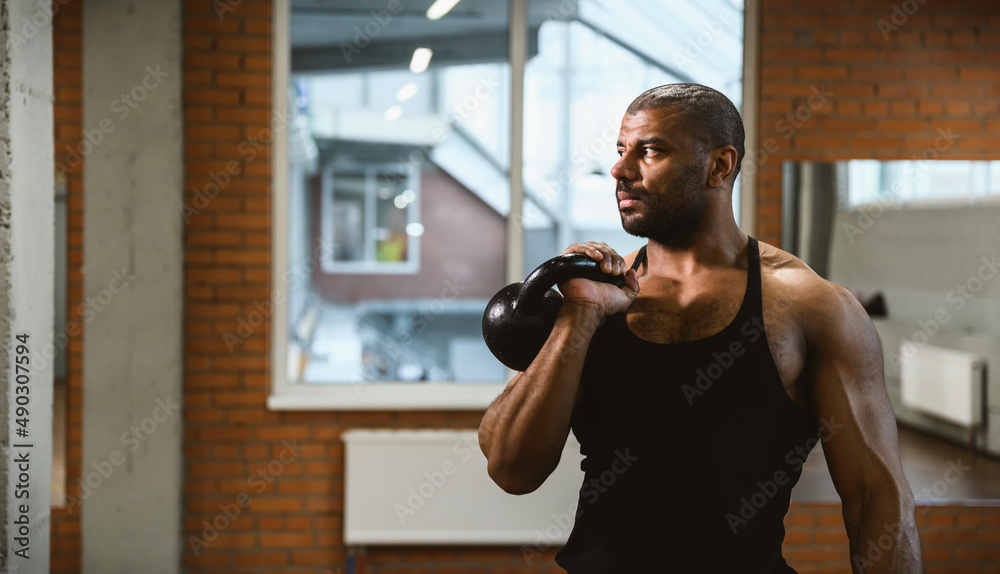 Close up portrait of African American muscular man lifting a kettlebell at gym. Close up portrait of African American muscular man lifting a kettlebell at gym.