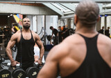 Muscular afro-american man working out in gym doing exercises with dumbbells at shoulders without coach or instructor. Fitness crossfit bodybuilding concept