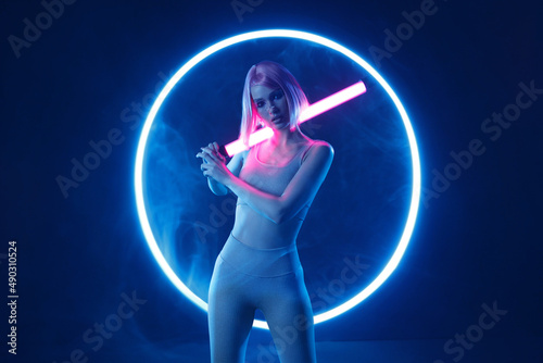 Woman in futuristic costume. Female in modern VR glasses interacting with network while having virtual reality experience. Augmented reality game, future technology, AI concept. VR. Neon blue light. © KDdesignphoto