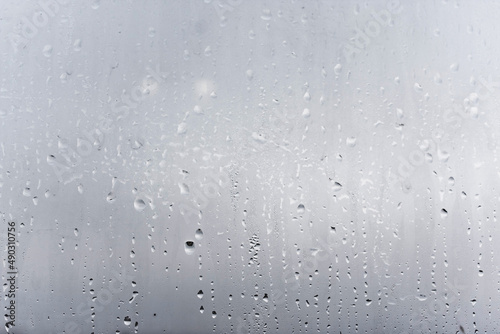 Steamy window with water drops made in dull day, condensation on glass with drops flowing down, humidity and foggy blank © Aleksandr