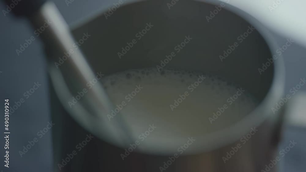 Shaking milk with a cappuccinatore in a metal pinscher. The process of preparing fresh coffee and cappuccino Shaking milk with a cappuccinatore in a metal pinscher. The process of preparing fresh coffee and cappuccino
