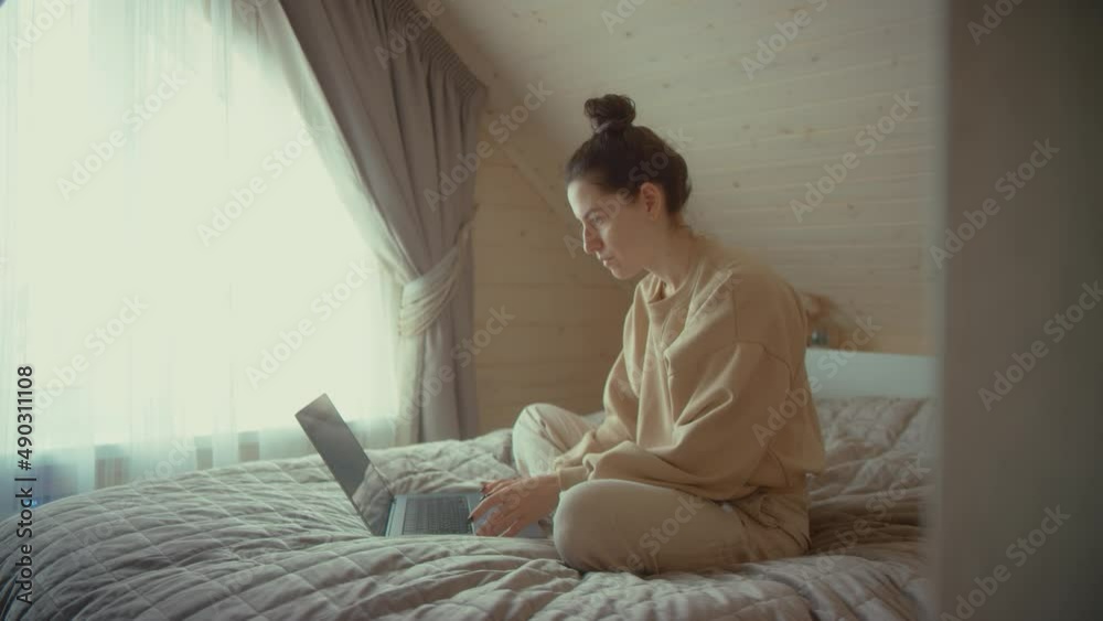 Concentrated woman works on laptop. Female freelancer uses modern PC. Lady rests on bed with notebook. Female blogger home workplace. 4K footage Concentrated woman works on laptop. Female freelancer uses modern PC. Lady rests on bed with notebook. Female blogger home workplace. 4K footage