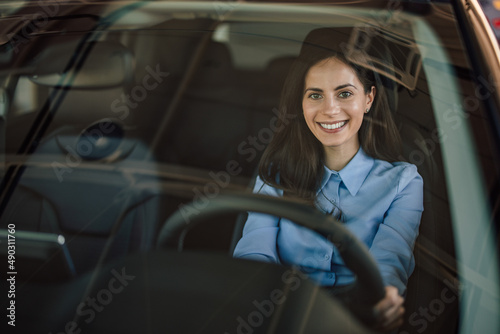 Portrait of joyful caucasian woman, satisfied with the car she b