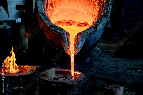 Molten and red-hot metal flows out of the ladle. soft focus