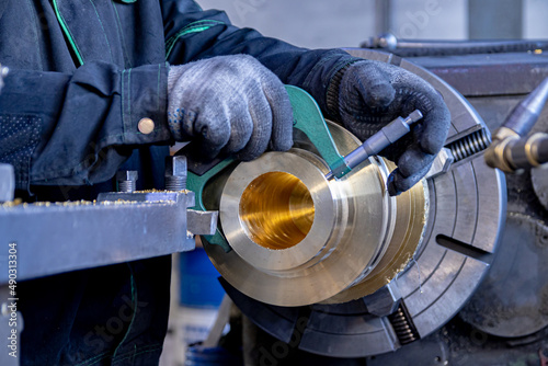 The specialist measures the manufactured part fixed in the lathe. Soft focus